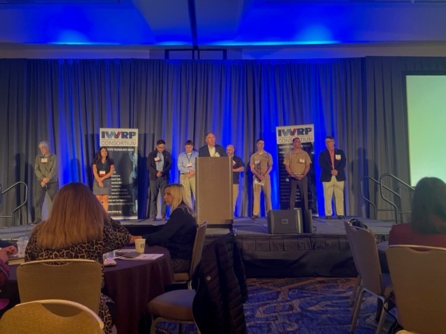 A presentation is about to begin with seven people with name tags standing on stage